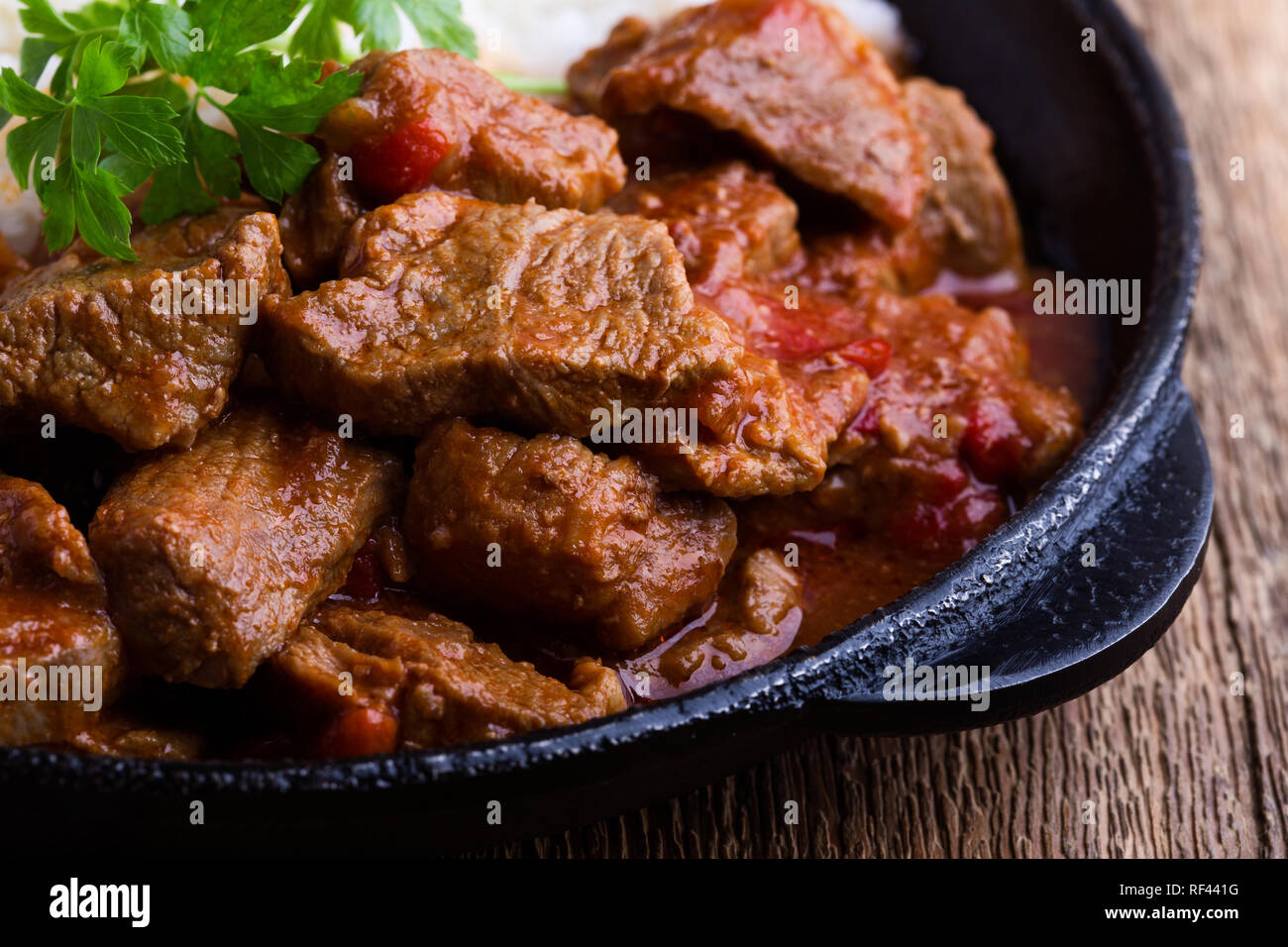 Ragoût de boeuf servi avec du riz blanc dans la poêle en fonte sur table en bois rustique, close-up, selective focus Banque D'Images