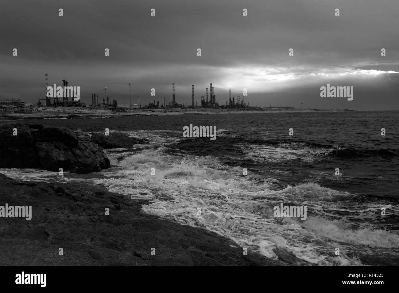 Paysage marin noir et blanc au crépuscule voir une grande raffinerie de pétrole dans l'arrière-plan. Utilisé filtre infrarouge. Banque D'Images