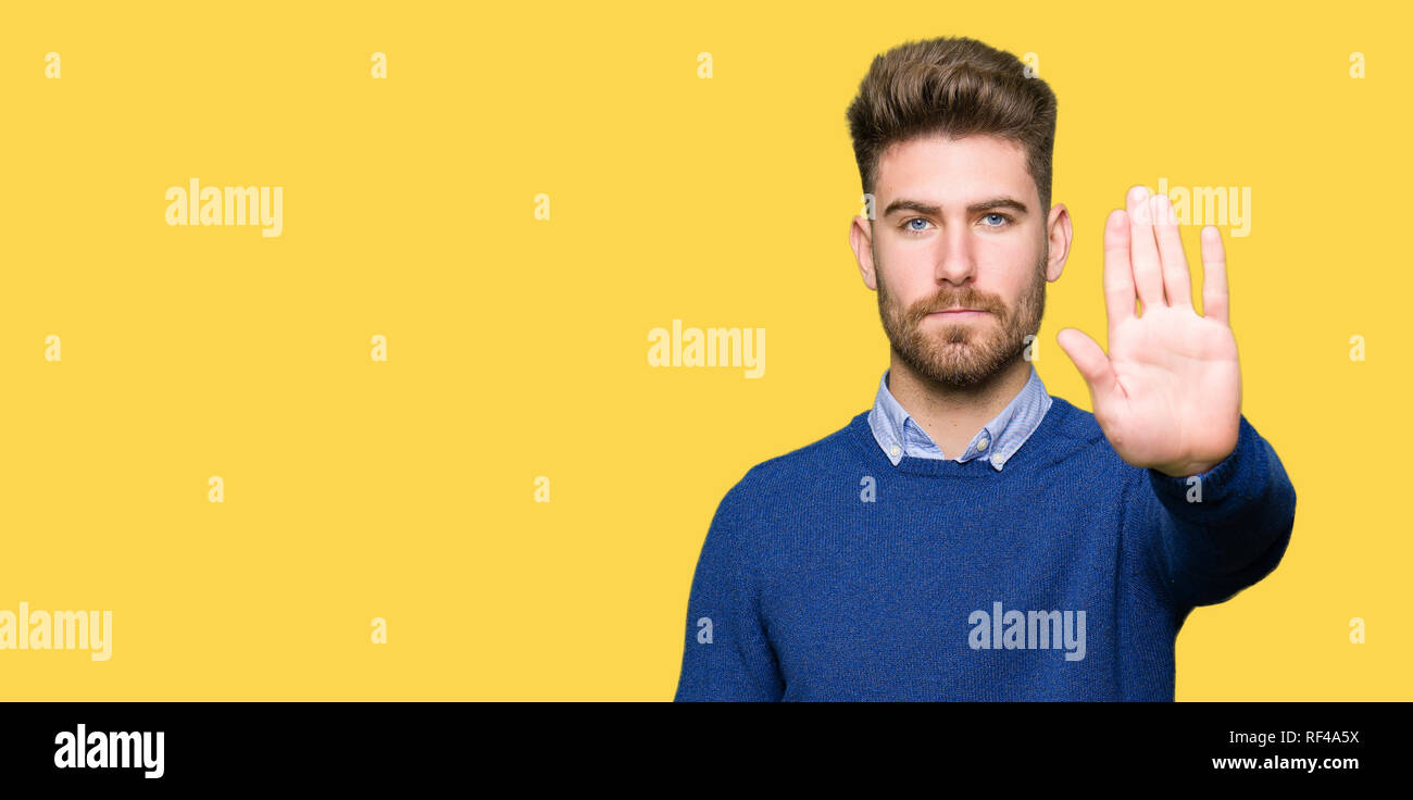 Beau jeune homme d'affaires faisant arrêter de chanter avec paume de la main. Expression d'avertissement avec négatif et geste sérieux sur le visage. Banque D'Images