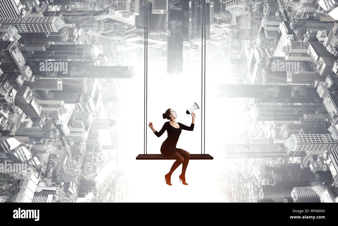 Femme mime dans un costume noir assis sur swing. Technique mixte Banque D'Images