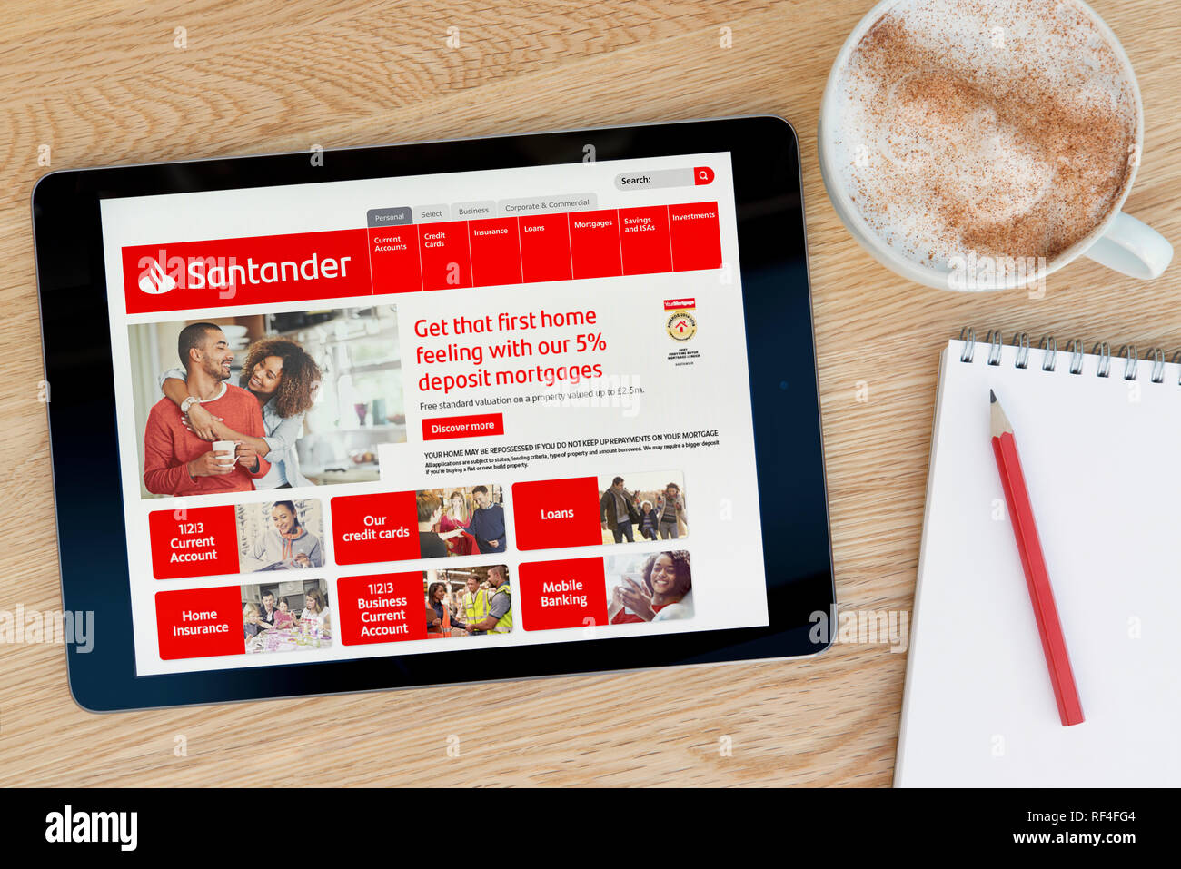 Le site web de la Banque Santander dispose sur un iPad tablet device qui repose sur une table en bois à côté d'un bloc-notes (Editorial uniquement). Banque D'Images