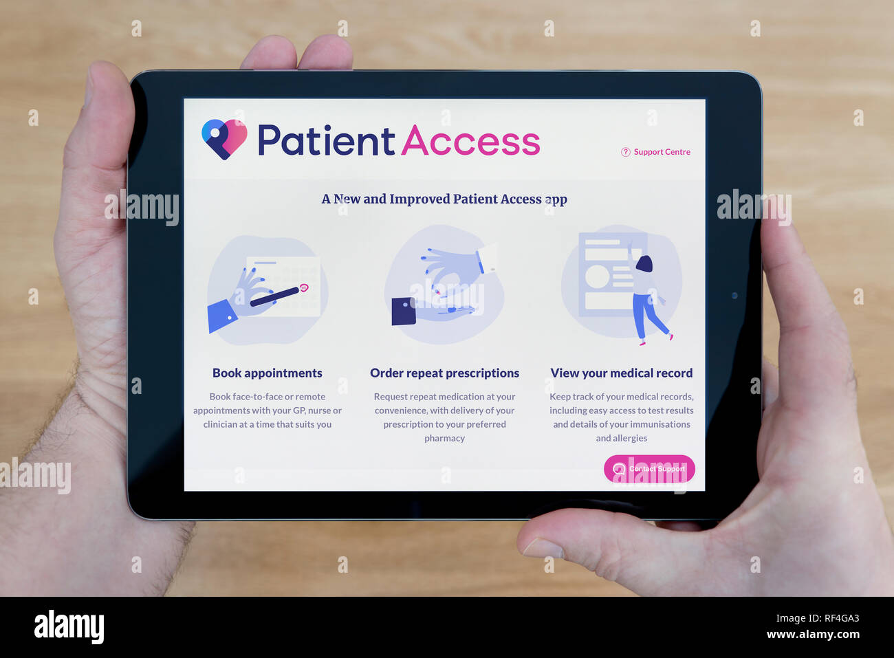 Un homme se penche sur le site web d'Accès Patient sur son iPad tablet device, tourné contre une table en bois page contexte (usage éditorial uniquement). Banque D'Images