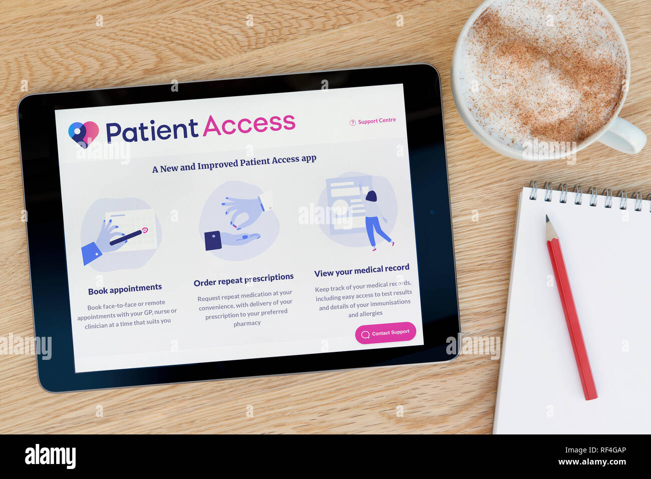 L'accès des patients aux fonctionnalités du site web sur un iPad tablet device qui repose sur une table en bois à côté d'un bloc-notes (Editorial uniquement). Banque D'Images