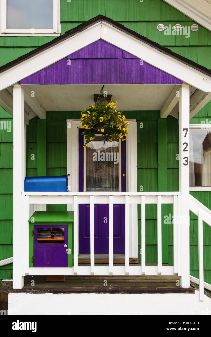 Porche et porte d'une ancienne maison à ossature bois historique dans la région de Juneau, Alaska avec revêtement bardeaux peints de couleurs vives Banque D'Images