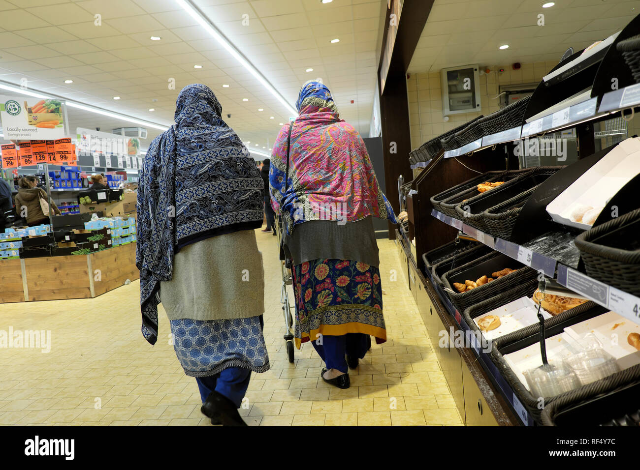 Lidl supermarché shoppers deux personnes âgées vieux femmes portant le foulard foulard ensemble commercial passé marche boulangerie vide étagères en UK KATHY DEWITT Banque D'Images