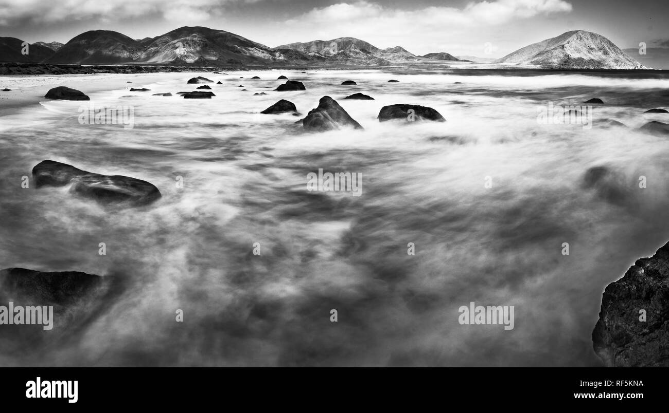 L'eau se déplaçant entre les rochers à une plage sauvage dans le désert d'Atacama. Le mouvement de l'eau crée des formes dans l'eau sur une longue exposition Banque D'Images