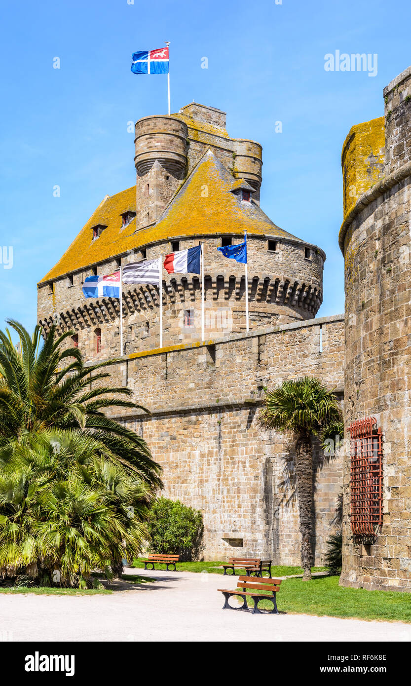 Le donjon du château de la Duchesse Anne de Bretagne dans la vieille ville de Saint-Malo, France, avec des drapeaux au vent au-dessus du mur de la ville. Banque D'Images