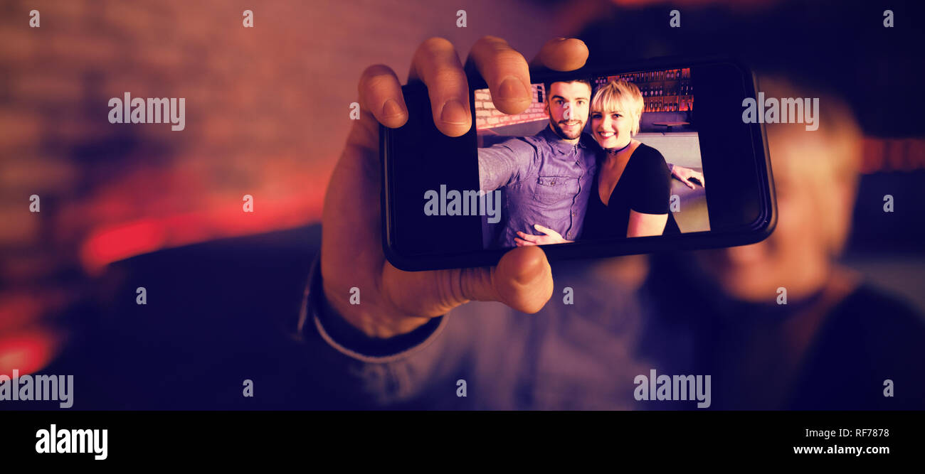 Couple sur téléphone mobile en selfies bar Banque D'Images
