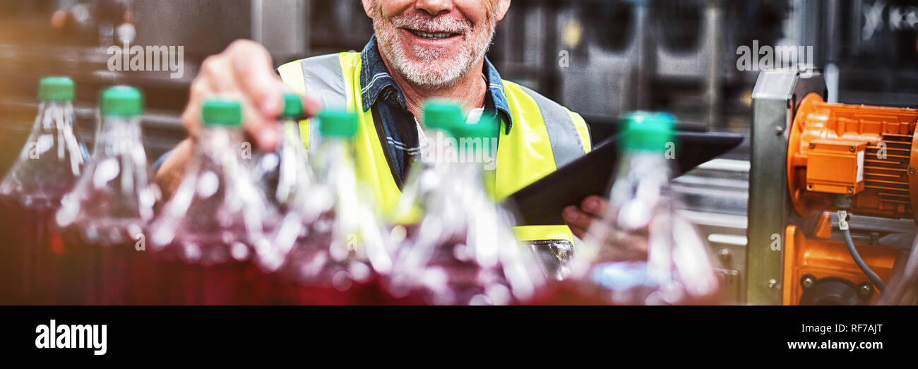La surveillance des travailleurs en usine mâle bouteilles de boisson froide Banque D'Images