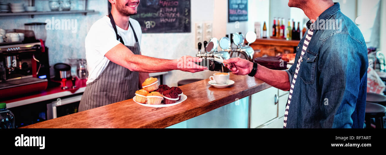 Client heureux de payer par carte de crédit au café Banque D'Images