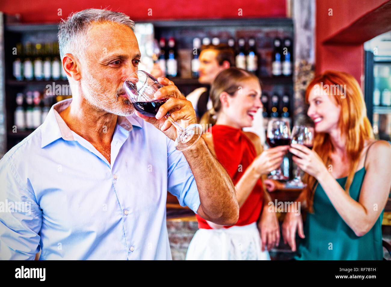 Man drinking red wine alors que deux friends toasting les verres en arrière-plan Banque D'Images