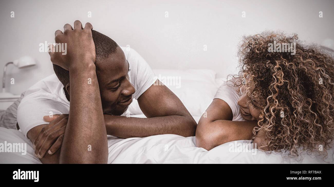 Jeune couple lying on bed and talking Banque D'Images