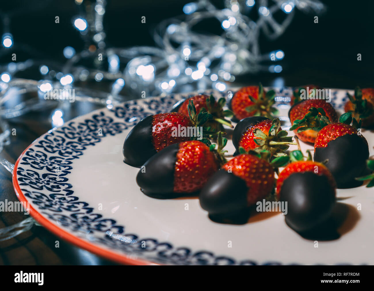 Fermer image de fraises au chocolat. Les fraises sur la plaque recouverte de chocolat et décoré avec des lumières. Banque D'Images