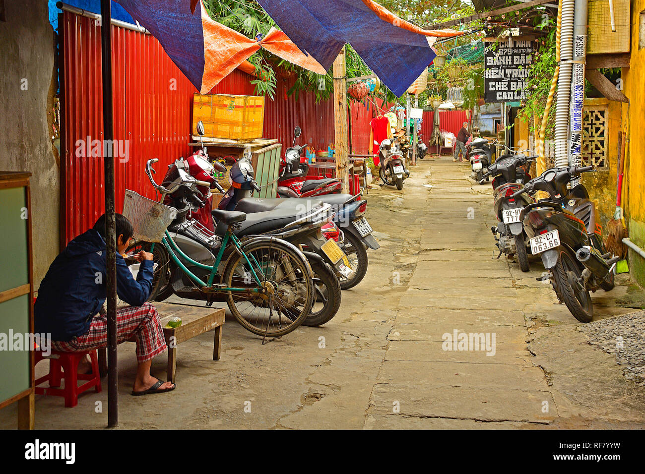 Hoi An, Vietnam - 20 décembre 2017. Un homme mange son déjeuner dans une rue calme à l'arrière de sa maison à l'écart des foules de touristes remplissant Banque D'Images