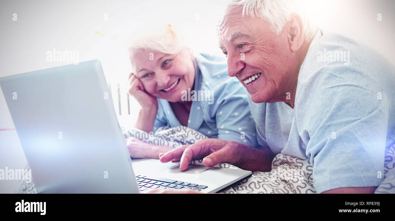 Senior couple using laptop in bedroom Banque D'Images