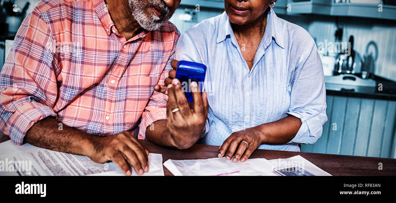 Couple using calculator en discutant par rapport au document Banque D'Images