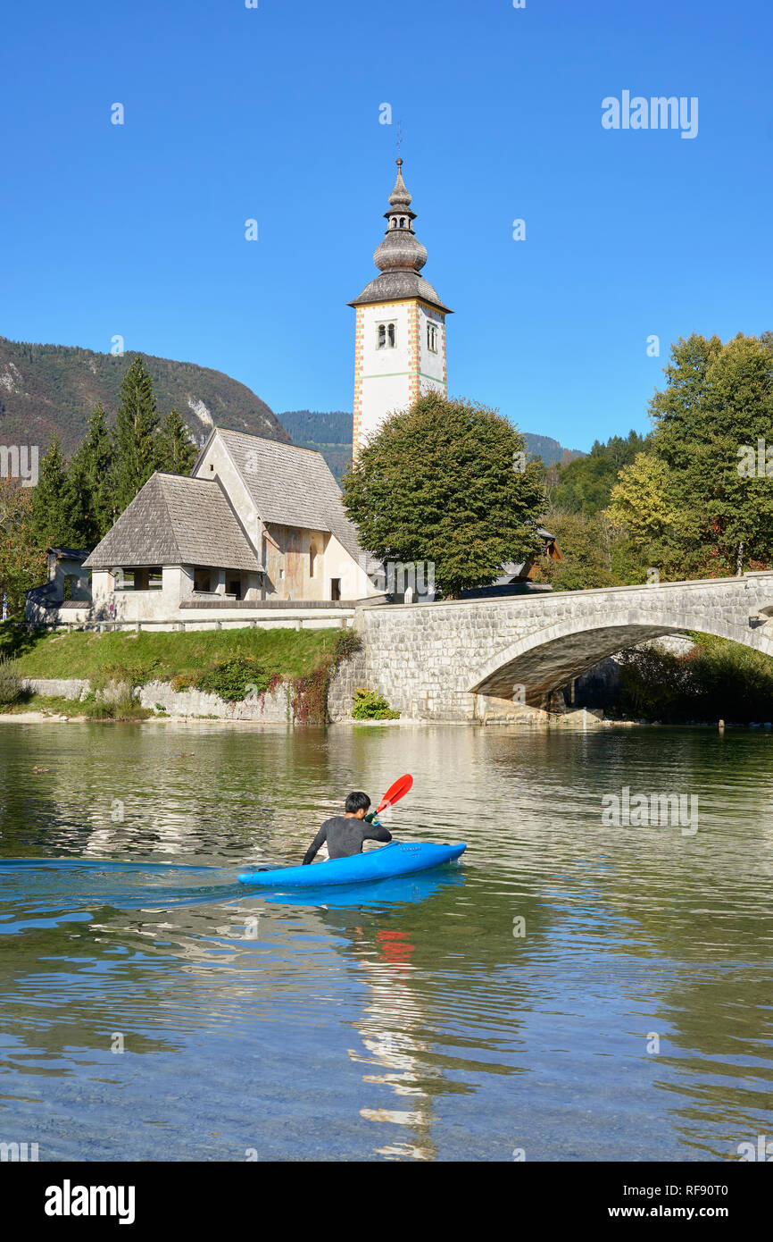 L'église de St Jean le Baptiste, Cerkev Sv. Janeza Krstnika, et le lac de Bohinj, Bohinj, Ribcev Laz, Haute-Carniole, la Slovénie. Avec les canoéistes sur le lac Banque D'Images