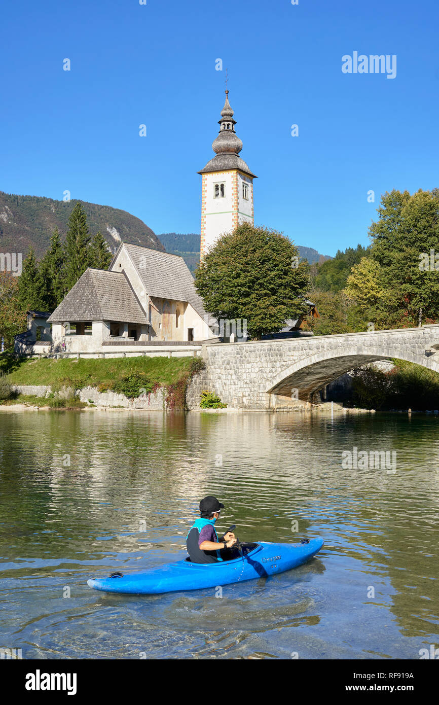 L'église de St Jean le Baptiste, Cerkev Sv. Janeza Krstnika, et le lac de Bohinj, Bohinj, Ribcev Laz, Haute-Carniole, la Slovénie. Avec les canoéistes sur le lac Banque D'Images