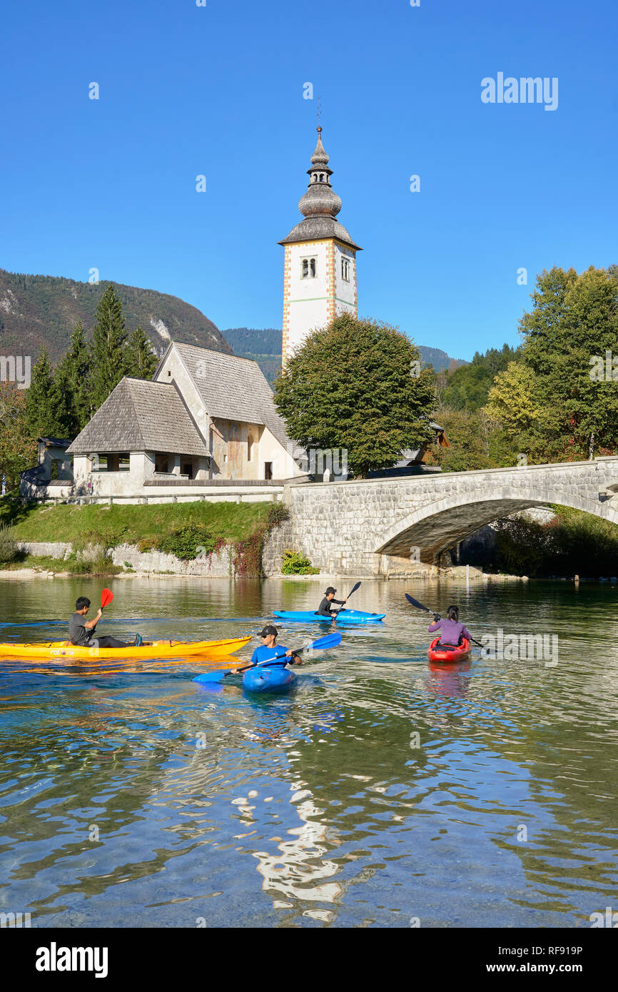 L'église de St Jean le Baptiste, Cerkev Sv. Janeza Krstnika, et le lac de Bohinj, Bohinj, Ribcev Laz, Haute-Carniole, la Slovénie. Avec les canoéistes sur le lac Banque D'Images