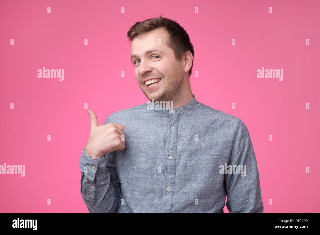 Heureux bel homme en chemise bleue showing Thumbs up Banque D'Images