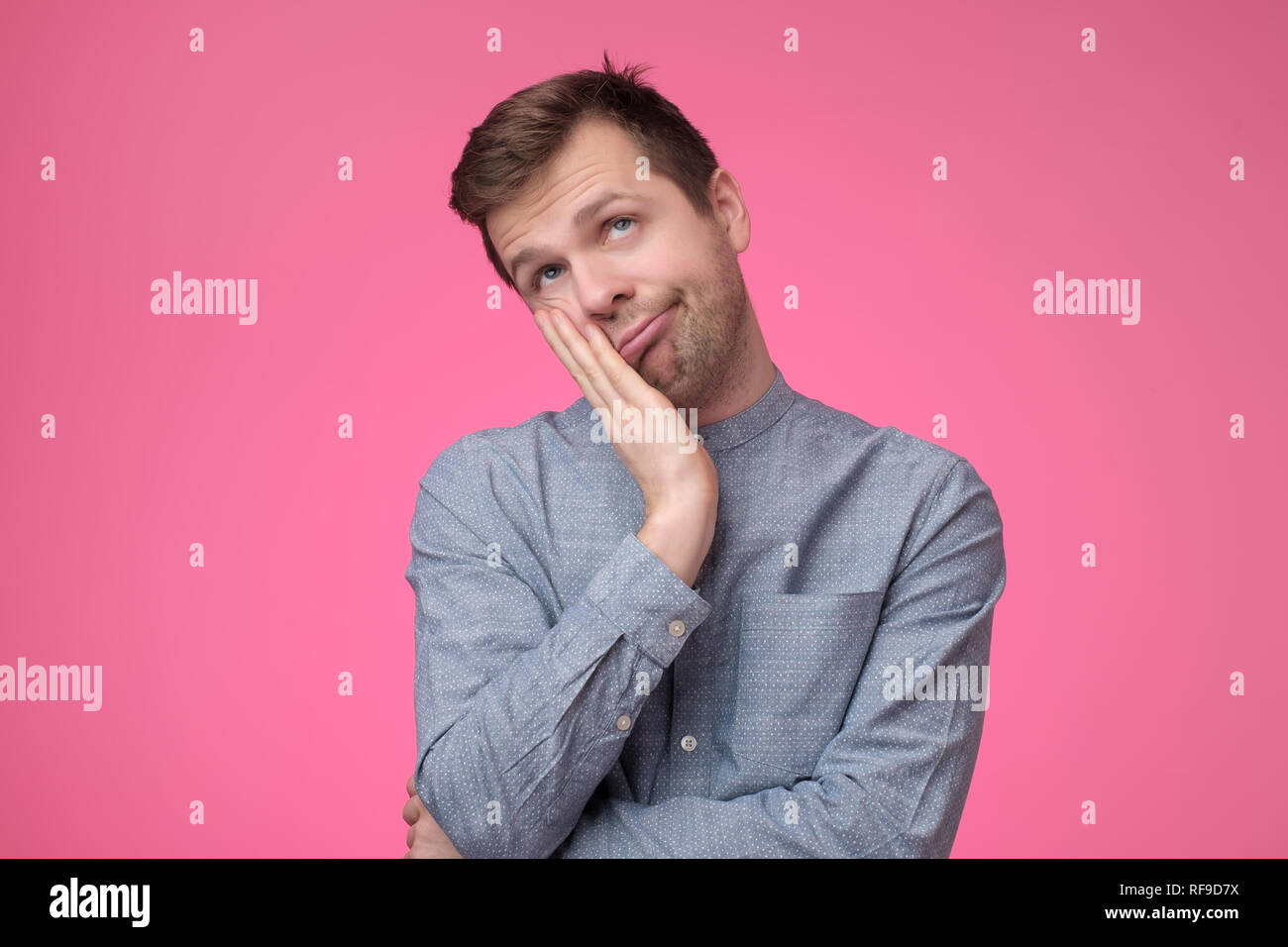 Happy funny guy holding paumes sur les joues s'appuyant sur les mains et souriant avec affection Banque D'Images