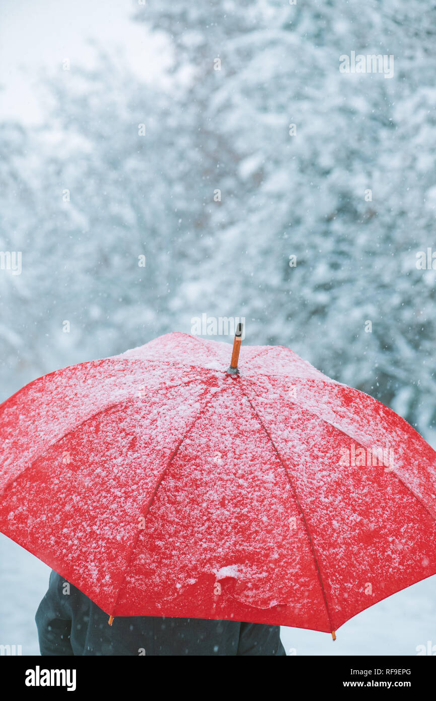 Femme sous parapluie rouge dans la neige profiter de la première neige de la saison d'hiver Banque D'Images