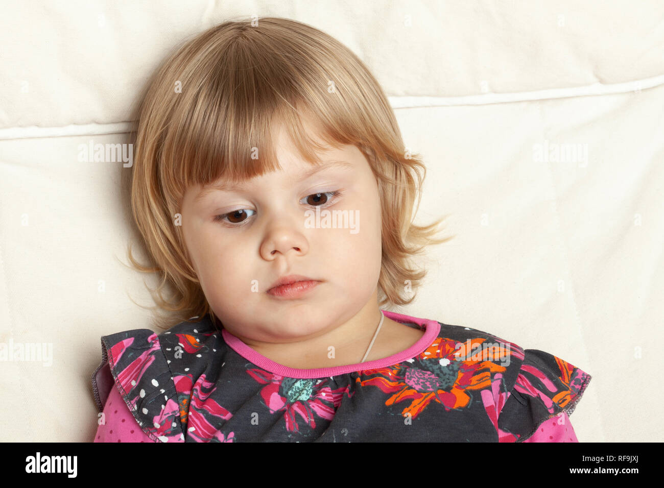 Portrait grave mignon petite fille assise dans la chaise blanche, closeup portrait studio Banque D'Images