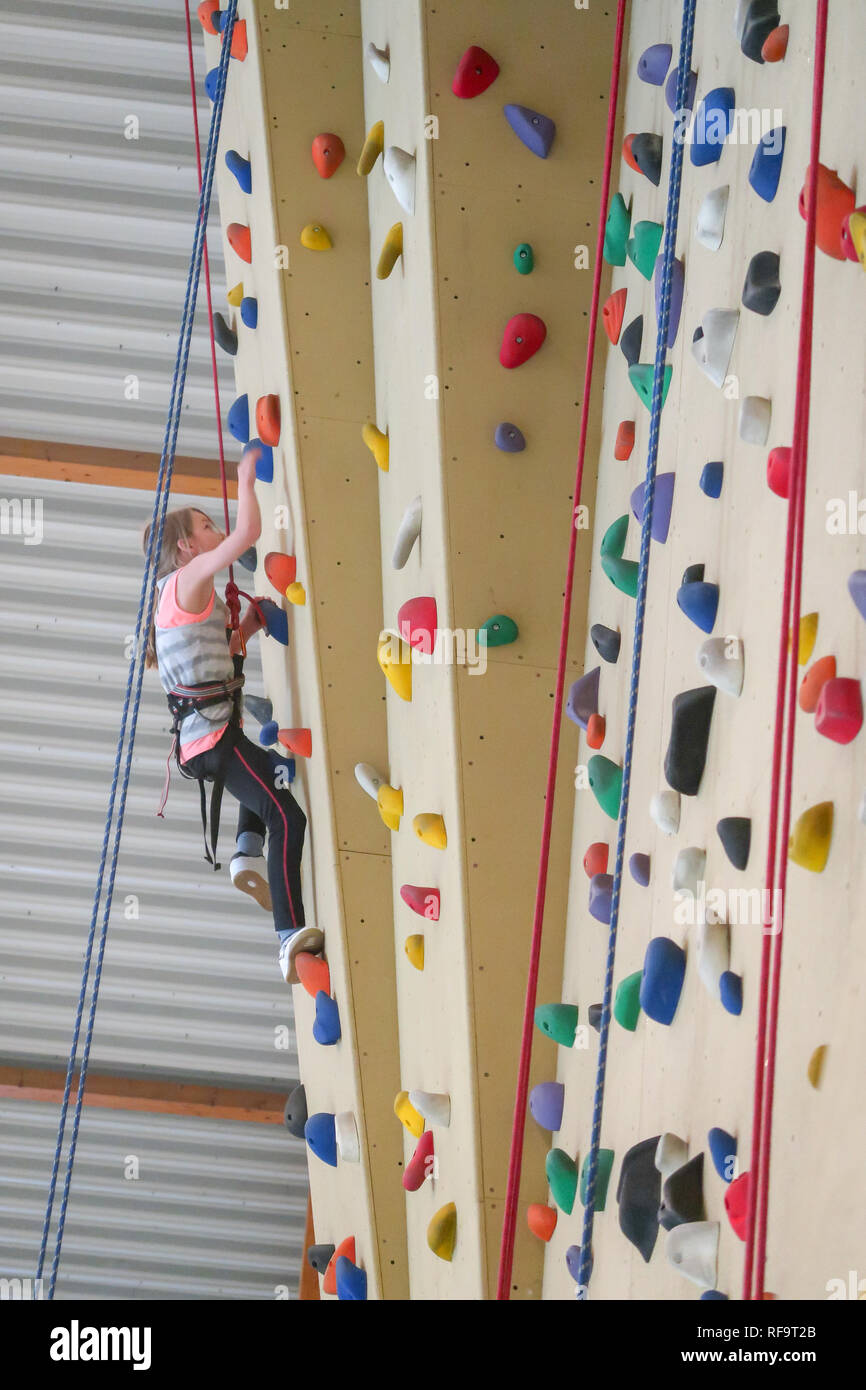 Une fillette de 9 ans grimpe un mur d'escalade dans un surplomb Banque D'Images