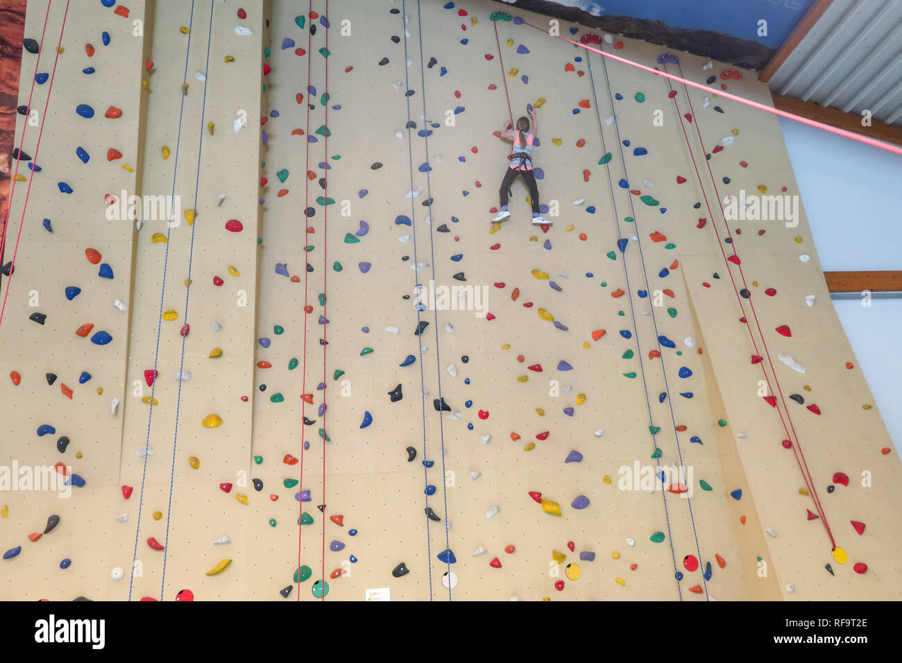 Une fillette de 9 ans grimpe un mur d'escalade Banque D'Images