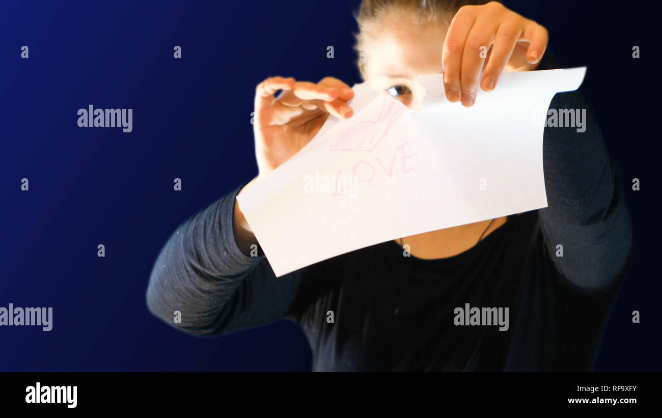 Teenage girl holding un signe de papier dans sa main avec un coeur dessiné ci-dessus, l'extraction de séquences, il idéal pour représenter les émotions d'amour et de rapport d'amour Banque D'Images