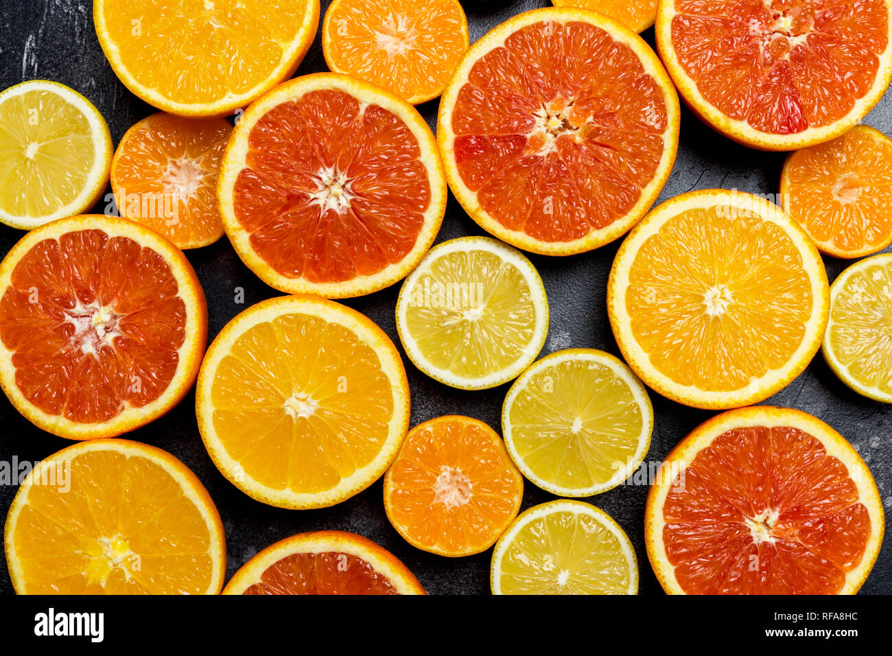 Fond d'agrumes colorés avec orange, pamplemousse, citron, mandarine à fond sombre Banque D'Images