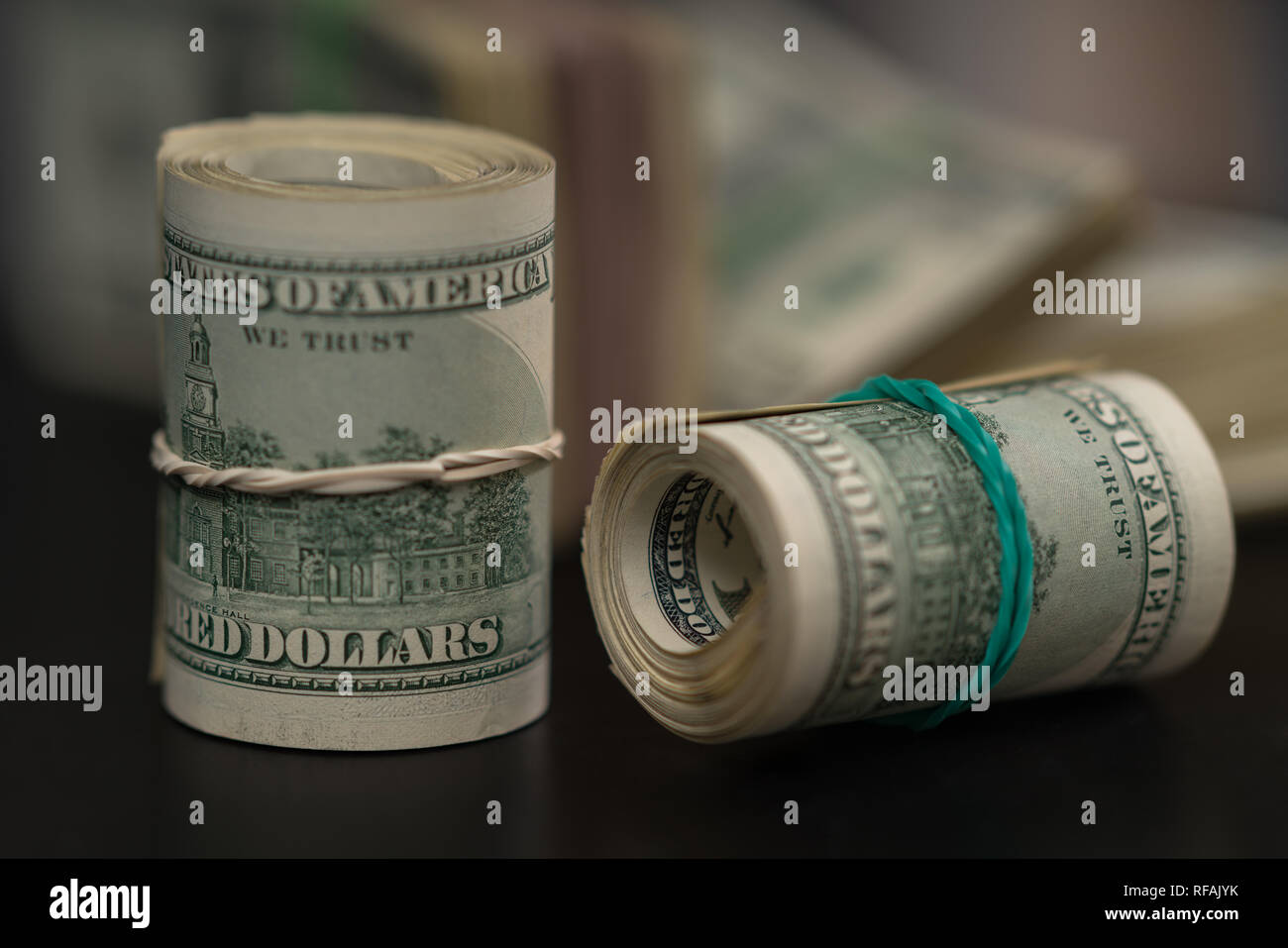 Deux rouleaux de factures USD laminées à égalité avec les bandes de caoutchouc l'une verticale et l'autre sur le côté, sur un tableau noir dans une image conceptuelle ou la corruption financière Banque D'Images