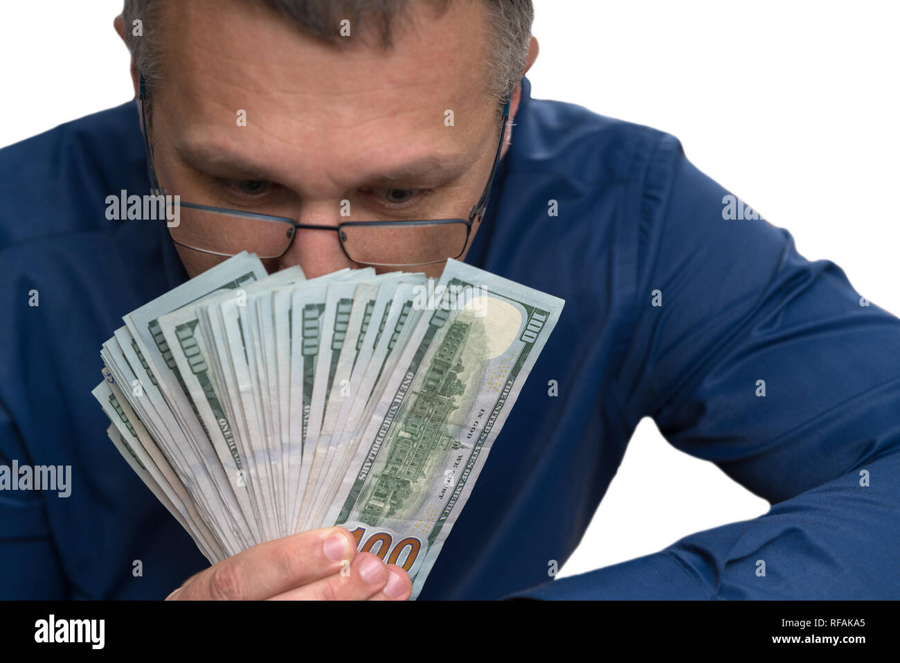 Thoughtful man holding a attisé poignée d'argent avec les billets de 100 USD à bas les tenant en face de son visage dans une image conceptuelle Banque D'Images
