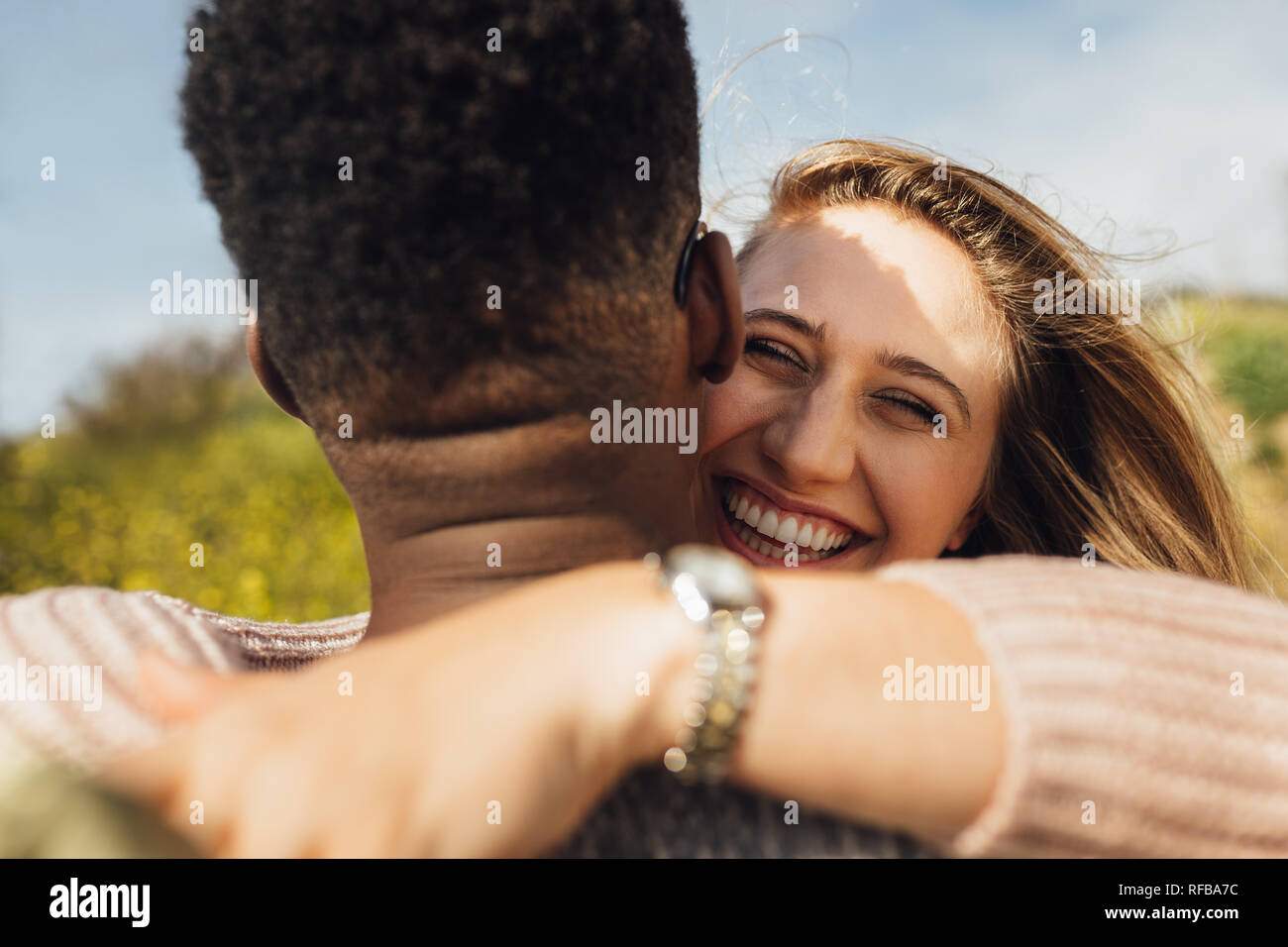 Cheerful woman embrassant son petit ami. Couple interracial romantique en plein air. Banque D'Images