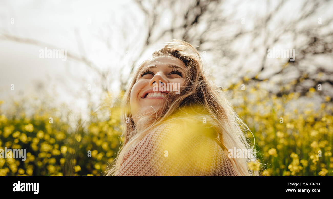 Close up of young woman sitting in prairie de fleurs jaunes à l'extérieur. Les femmes de race blanche à l'écart et souriant. Banque D'Images