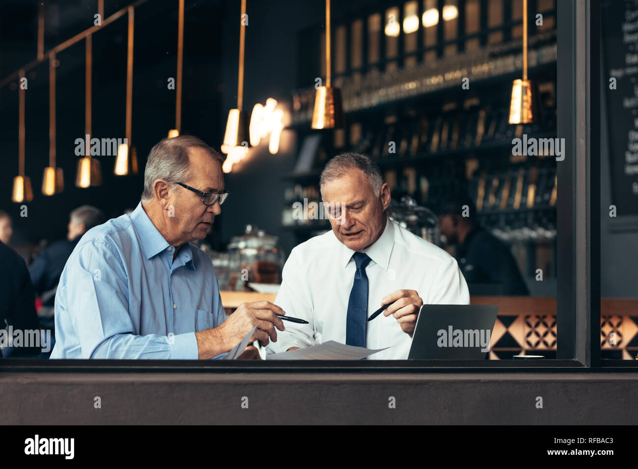 Deux personnes dans le restaurant par une séance de brainstorming sur la fenêtre Projet. Les hommes d'affaires de discuter d'un document dans un café. Banque D'Images