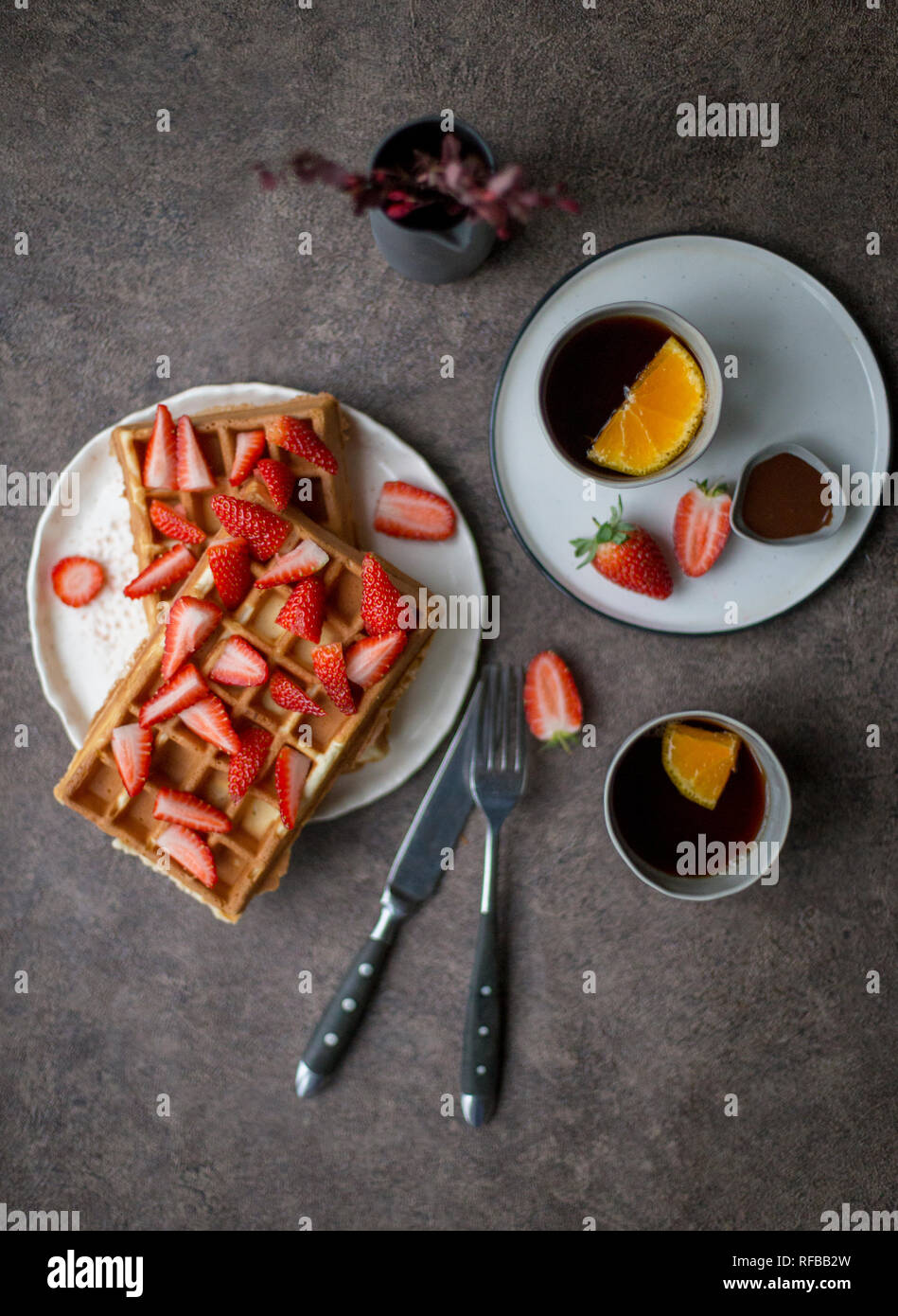 Sweet Belgique gaufres avec fraise à plaque blanche et deux tasse de thé au citron à l'arrière-plan sombre. Concept de style de vie sain pour le menu Banque D'Images
