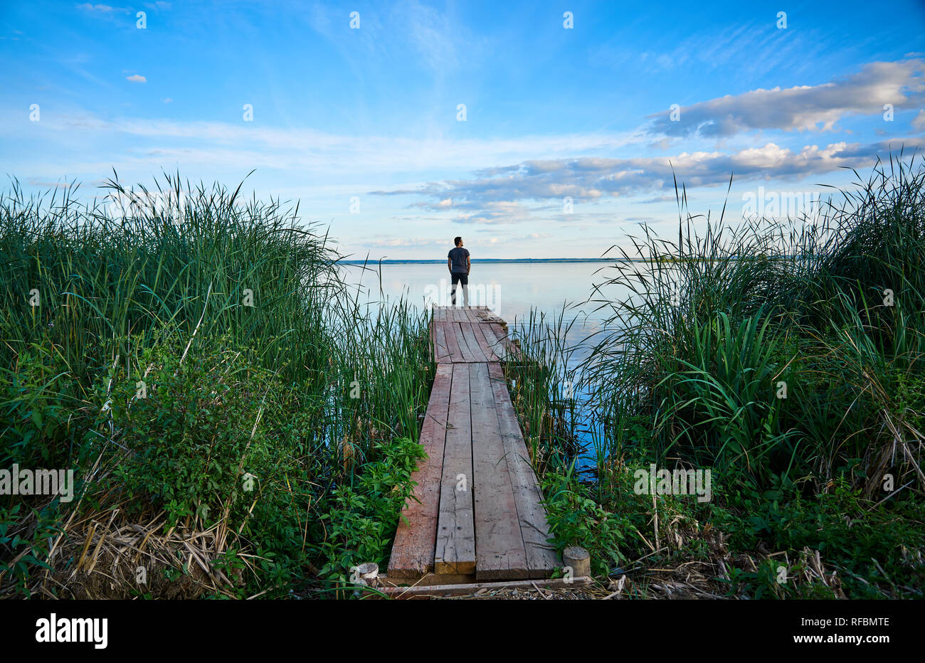 L'homme se tient sur une jetée en bois sur le lac Nero, près de Rostov le Grand, Golden Ring, Russie. Banque D'Images