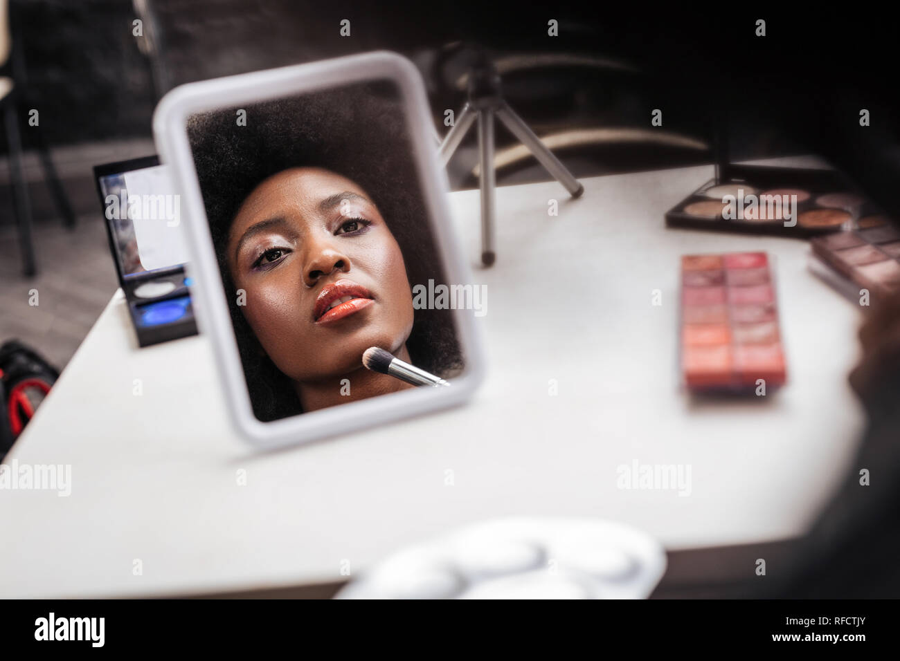Belle femme africaine avec des cheveux bouclés faisant un miroir Banque D'Images