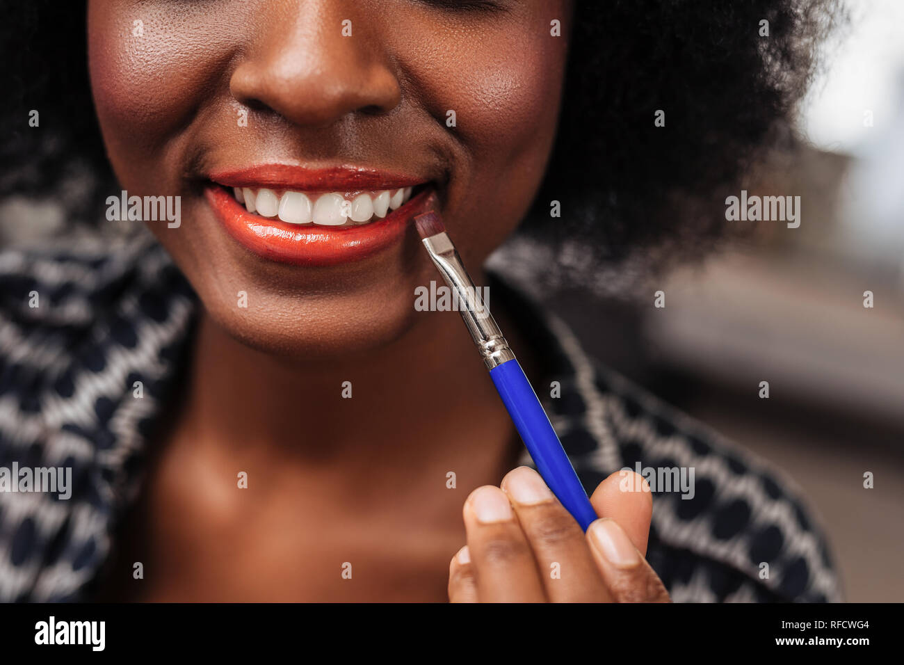African American Woman incroyable avec des cheveux bouclés bénéficiant du processus de maquillage Banque D'Images