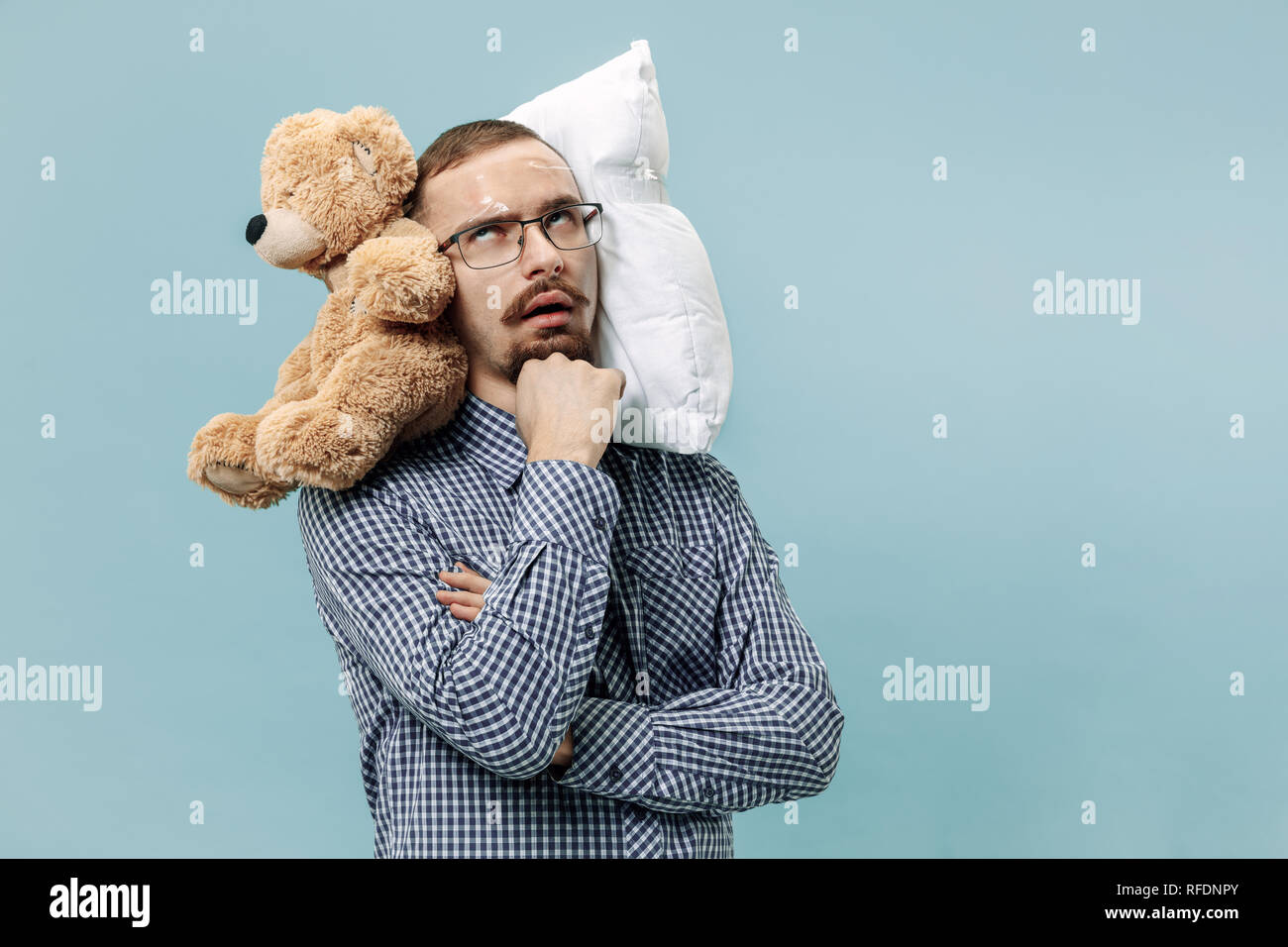 Homme fatigué dormir à la maison ou au bureau d'avoir trop de travail. Homme d'ennuyer avec oreiller et ours en peluche. L'occupé, plate, inquiets, être en retard, le sommeil, jour, concept introuble Banque D'Images