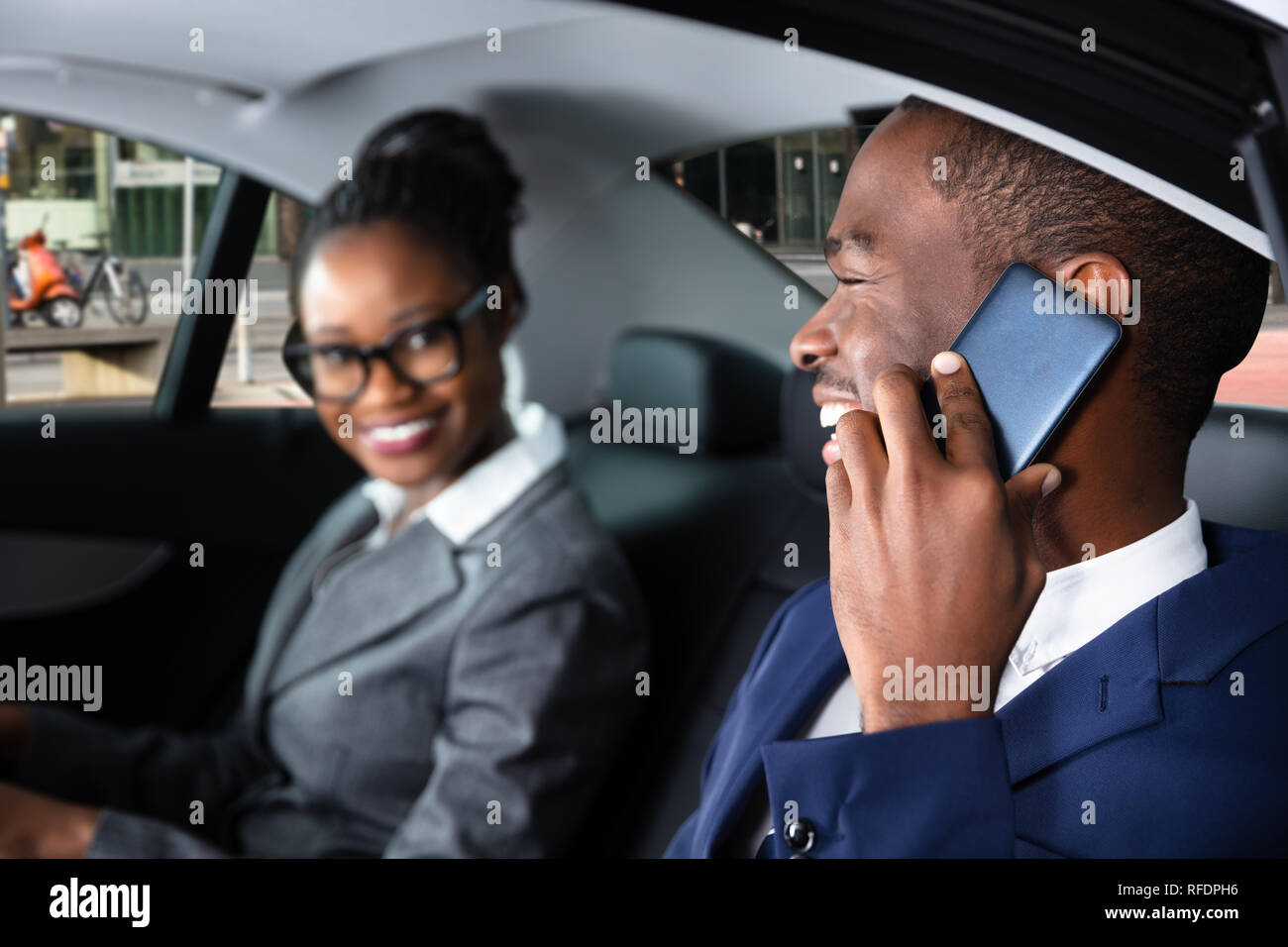 Portrait assis à l'intérieur de voiture à côté de son collègue Talking On Cellphone Banque D'Images