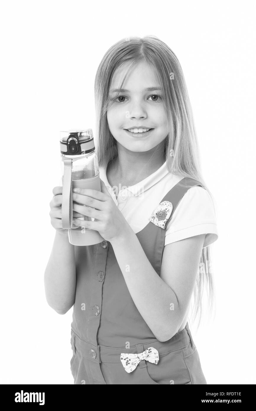 Petite fille sourire avec bouteille en plastique isolé sur blanc. Heureux l'enfant en pyjama rose Maintenez la bouteille d'eau. L'eau potable pour la santé. La soif et la déshydratation. L'activité de la petite enfance et de l'énergie. Banque D'Images