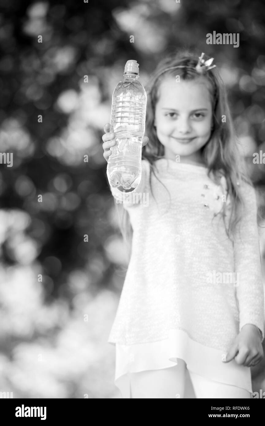 Bouteille d'eau dans la main du petit enfant floue sur fond naturel. Girl princess tenir l'eau douce. La soif et la déshydratation. Rafraîchissement et de fraîcheur. L'enfance et de la garde d'enfants, noir et blanc. Banque D'Images