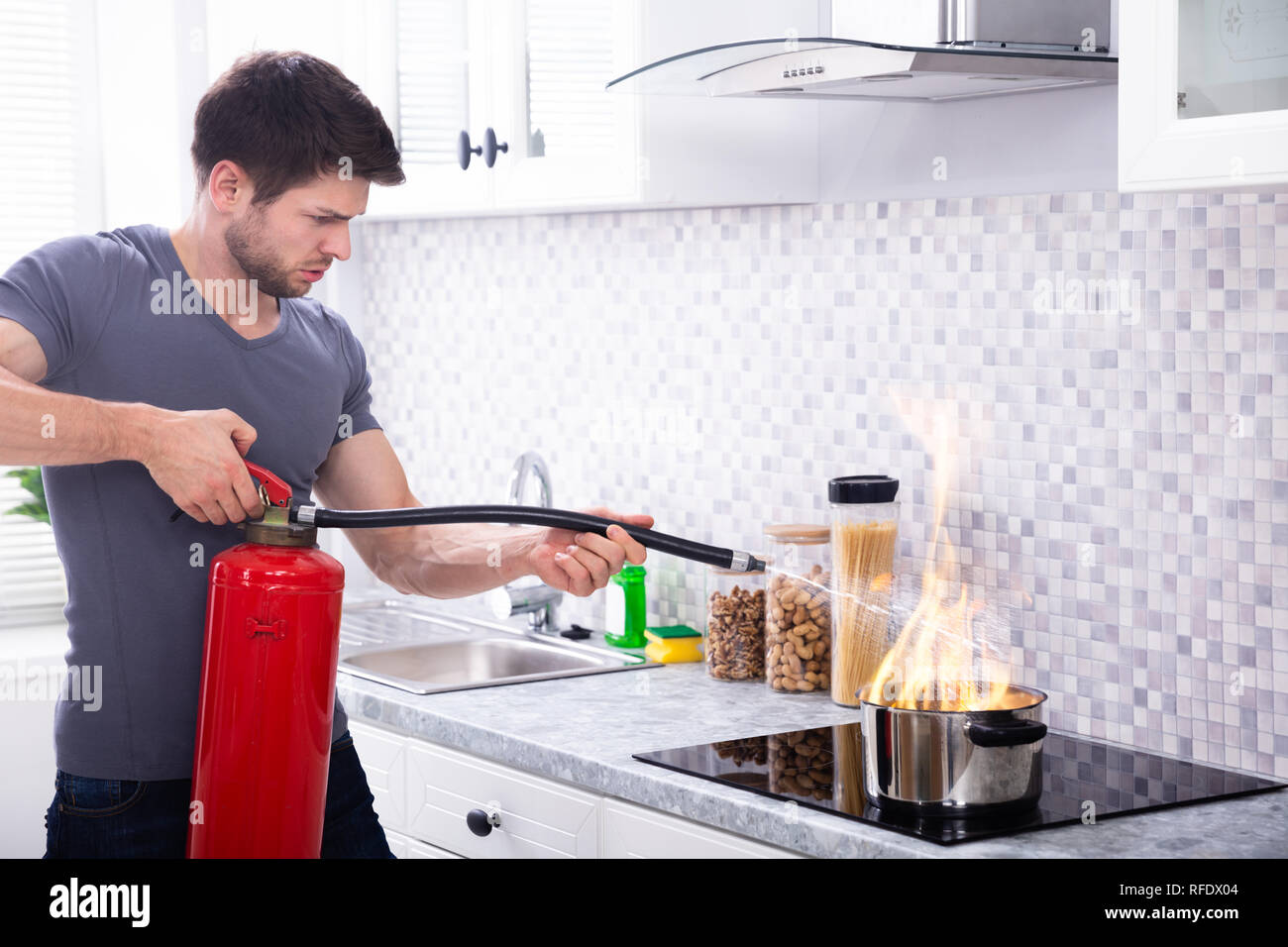 L'homme à l'aide d'extincteur pour feu stop sur la gravure de casserole dans la cuisine Banque D'Images