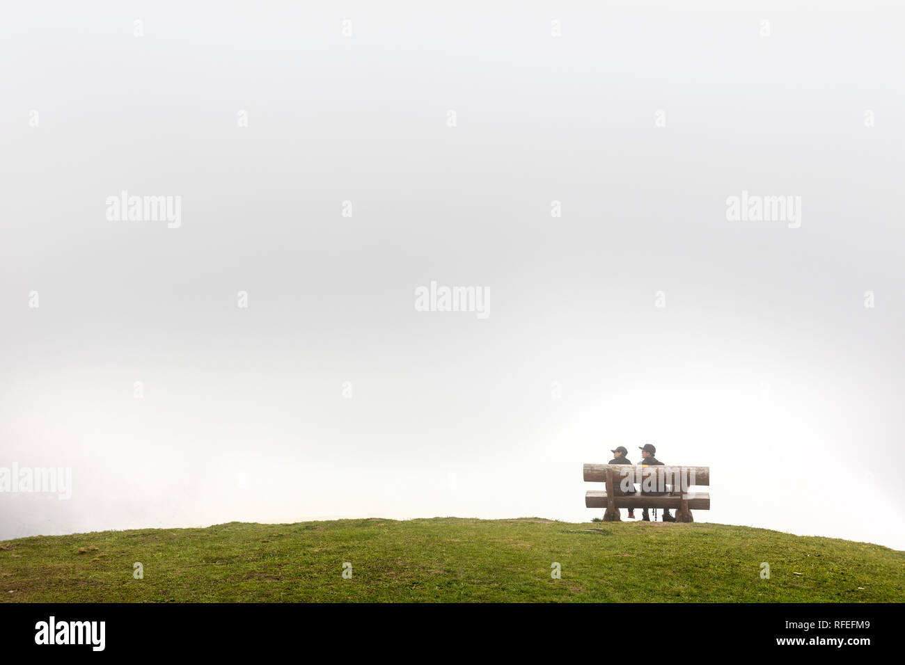 La Suisse, les Alpes, Berner Oberland, Grindelwald, printemps. Les hommes sur banc au premier sommet de la station de téléphérique. Le brouillard. Banque D'Images