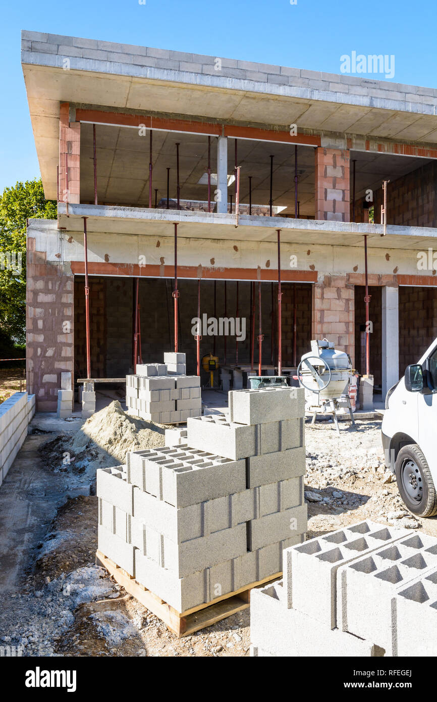 Blocs de béton empilés sur des palettes à l'extérieur devant une maison en construction dans la banlieue de Paris, France. Banque D'Images