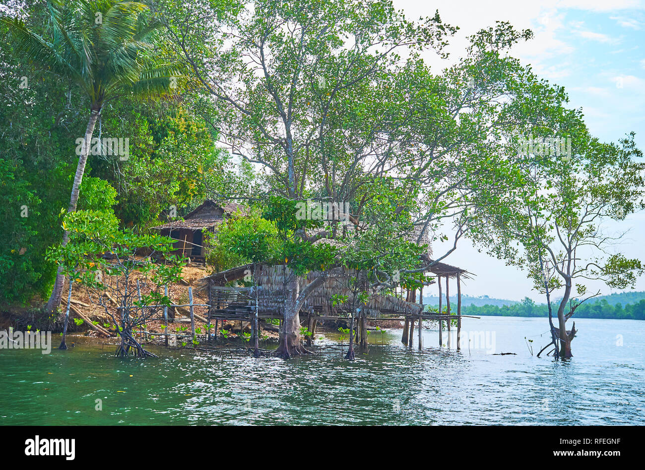 La vieille maison sur la colline et le squelette du nipa hut de pêche sur la rivière Kangy, Chaung Tha zone, le Myanmar. Banque D'Images