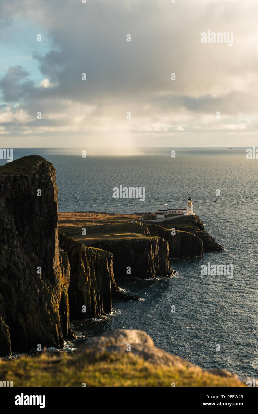 Coucher du soleil à Neist Point Lighthouse avec soleil, nuage de pluie, rude Côte et Ciel nuageux spectaculaires (Ile de Skye, Ecosse, Royaume-Uni, Europe) Banque D'Images