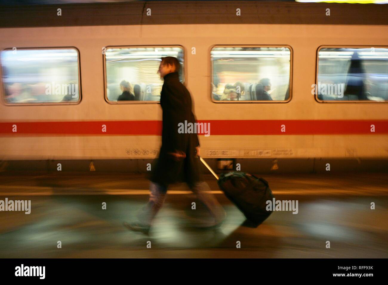 DEU Allemagne : Homme sur une plate-forme d'une gare ferroviaire en tirant sa valise trolley tandis qu'un train Intercity est de passage. | Banque D'Images